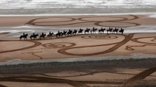 Evewright kreslí do písku na pláži chůzí koní a lidí