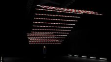 Barrier Bars je kinetická instalace 24 červenobílých tyčí tančících v černém prostoru